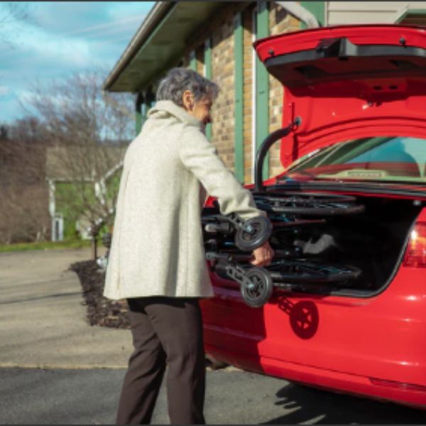 Lady storing away the Feather Lightweight Manual Wheelchair in the back trunk of  a car