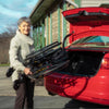 Lady storing away the Feather Lightweight Manual Wheelchair in the back trunk of a car