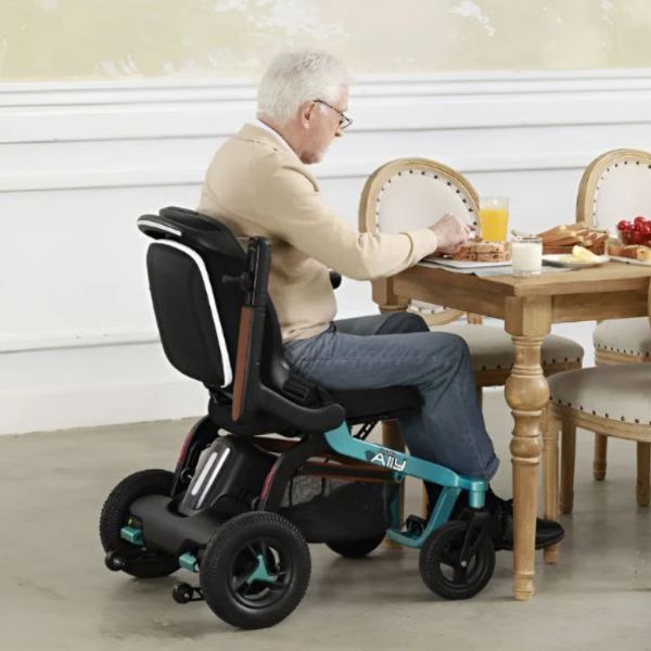 An elderly man in a Golden Ally power chair seated at a table