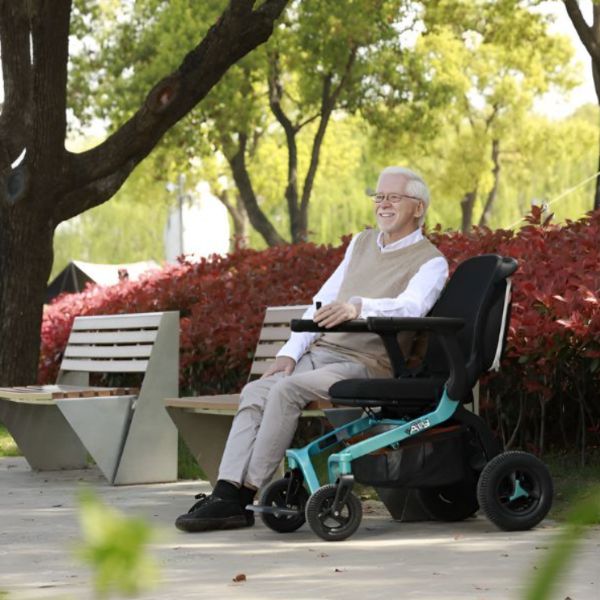 An elderly man in a Golden Ally power chair seated on a bench