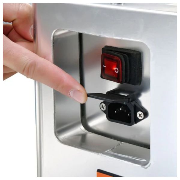 Hand pressing a switch on a metallic surface with a red light indicator.