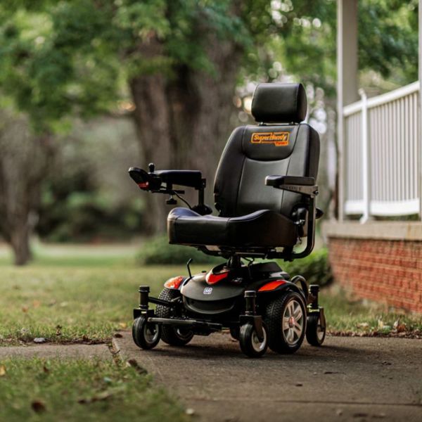 SuperHandy GoRide CRX Mid-Wheel Drive Power Wheelchair on a paved path with grass and trees in the background