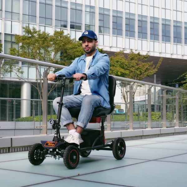 Man riding a Superhandy Explorer Heavy-Duty Mobility Scooter in an urban setting with modern buildings in the background