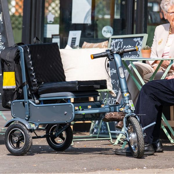Man and lady sitting with the eFOLDi Explorer Ultra Lightweight Mobility Scooter next to them