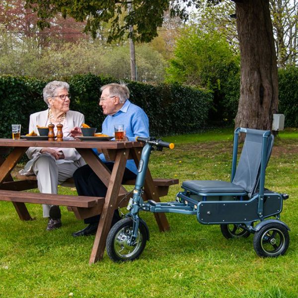 Man and lady sitting with the eFOLDi Explorer Ultra Lightweight Mobility Scooter next to them